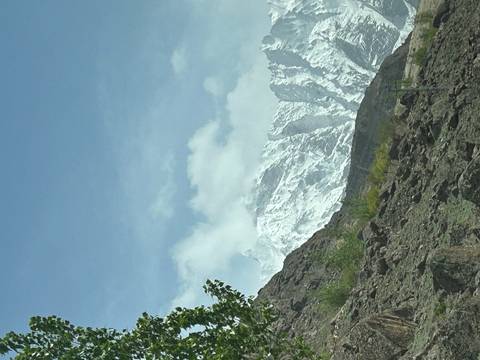 Snow-dusted mountain ridge emerging behind rocky slopes under a pale sky.