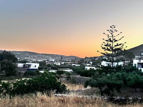 Dusky sky over a rural valley dotted with white houses and distant wind turbines on the hillside.