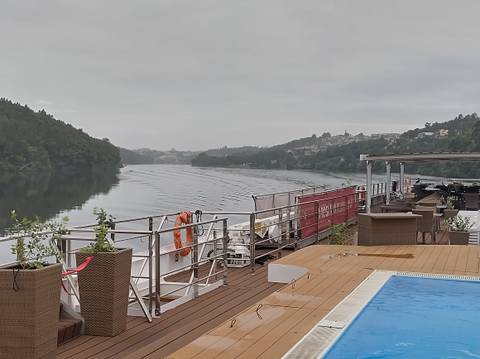 River cruise ship deck with pool on a calm misty morning cruising through a forested valley.