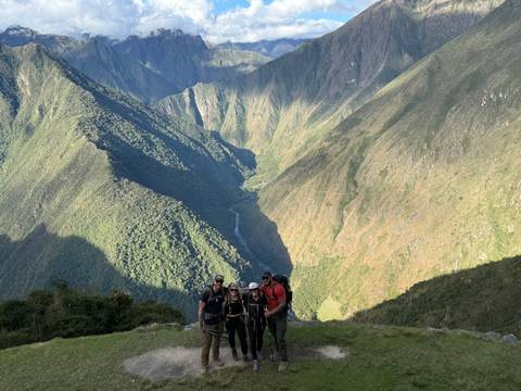 Hikers standing on a ridge overlooking dramatic green canyon-like valley