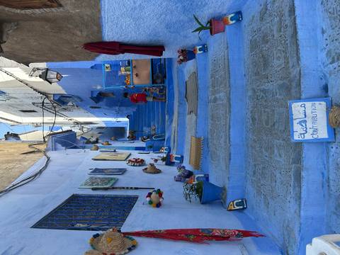 Iconic blue-painted staircase lined with crafts and pots in Chefchaouen medina