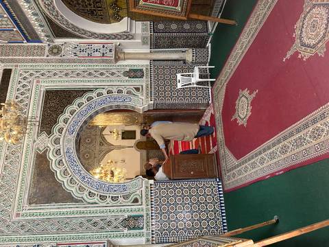 Ornate tiled entrance of a Moroccan mosque with worshippers entering