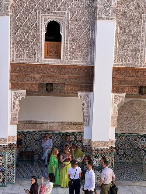 Detailed Moroccan arches and stucco carvings on white walls within a historic palace complex.