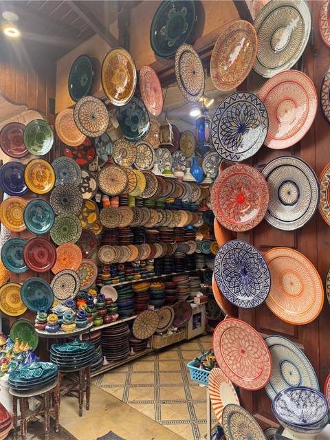Vibrant shop display of stacked and hanging hand-painted Moroccan ceramic plates in every colour.