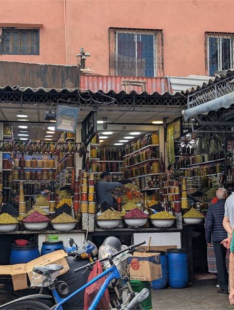 Olive and pickle vendor arranges colourful jars stacked high in a bustling food stall.