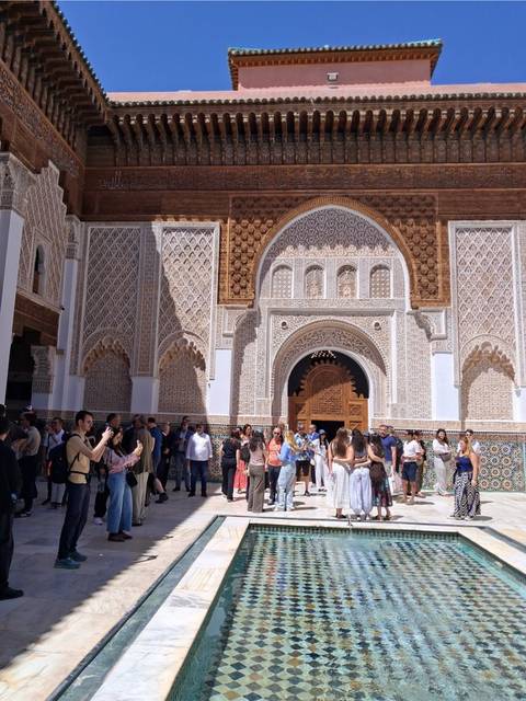 Ornate entrance of Medersa Ben Youssef with detailed tilework and crowds of visitors
