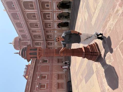 Visitor leans against a red sandstone lamp post in the spacious courtyard of Jaipur City Palace.