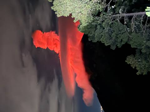 Nighttime eruption casts a red glow above Acatenango Volcano under a starry sky.