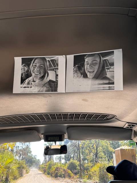 Snapshot of two printed black-and-white photos taped to a vehicle dashboard.