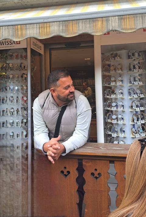 Man leans on wooden stall window browsing an array of wristwatches for sale.