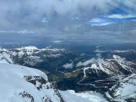 Snow-covered alpine peaks and deep valleys seen from high altitude with patches of clouds