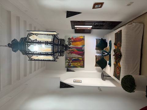Elegant riad bedroom with lantern chandelier, colorful art and towel swans on the bed.