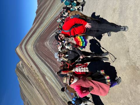 Visitors with llamas posing before the colourful layers of Peru's Rainbow Mountain amid a crowd