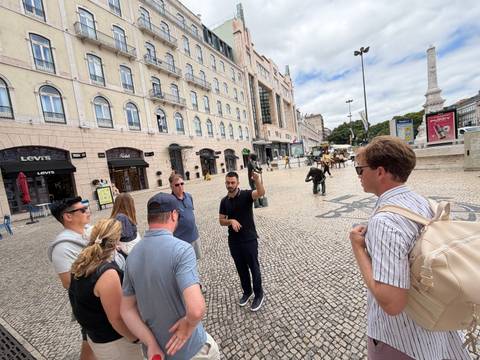 Tour guide speaking to travellers in a large stone plaza lined with historic buildings