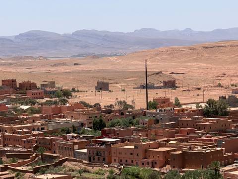 Desert town with flat-roofed adobe buildings set against arid plains and distant mountain range