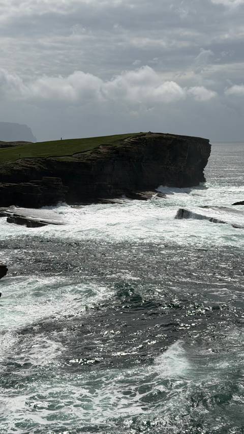 Powerful waves crashing against dark coastal cliffs sending white spray into the air