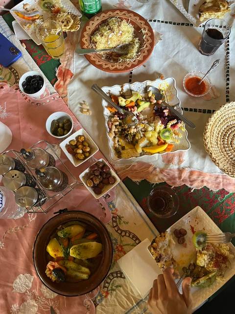 Colorful Moroccan breakfast spread with fruit, olives and small dishes on patterned tablecloths