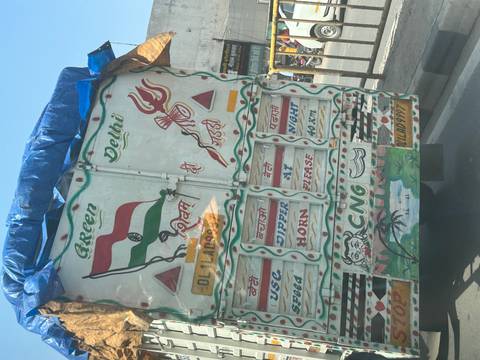 Rear view of a brightly painted Indian truck featuring slogans, symbols and the national flag.