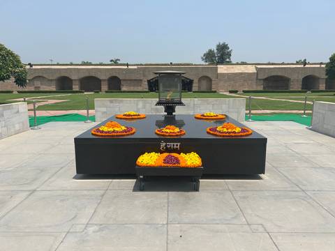 Black marble platform with an eternal flame and flower wreaths at Raj Ghat memorial.