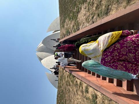 Visitors climb the stairs toward Delhi’s Lotus Temple under a cloudless blue sky.
