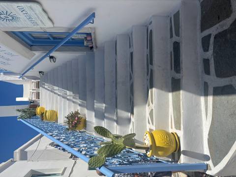 White marble staircase with blue railings and bright yellow planters leading up toward a deep blue sky.