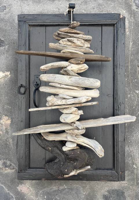 Artistic arrangement of weathered driftwood pieces mounted on a dark wooden background.