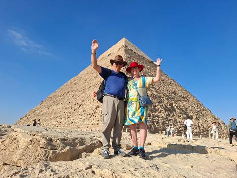 Happy couple waving in front of the Great Pyramid of Giza.