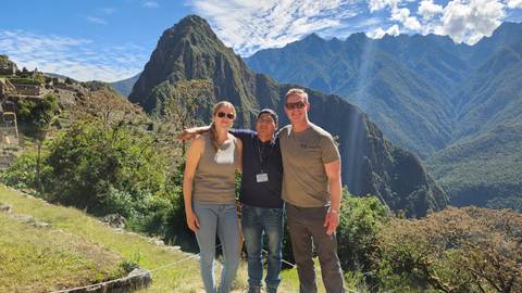 Travellers pose at a classic viewpoint overlooking the ancient terraces and peaks of Machu Picchu.