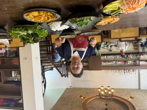 Cooking class setting with instructor serving multiple Vietnamese dishes at a dining table.