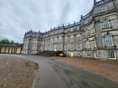 Grand stately home with neoclassical façade and wide staircase on a rainy day.