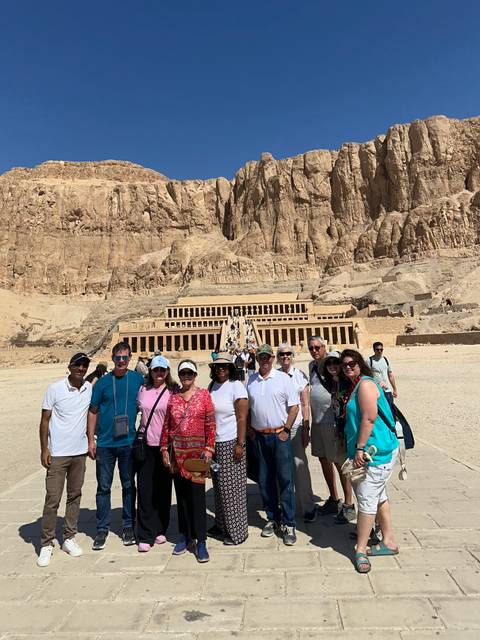 Tour group stands before the terraced Temple of Hatshepsut carved into the desert cliffs near Luxor.