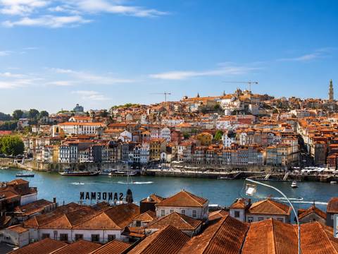 Panoramic view over the Douro River toward the terracotta rooftops and historic waterfront buildings of Porto.