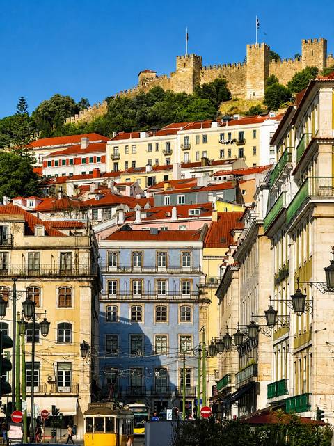 Compressed cityscape of Lisbon's Alfama district showcasing colorful buildings and red-tiled rooftops in warm golden light.
