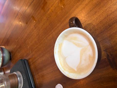 Partially sipped latte with heart-shaped foam art on wooden table.