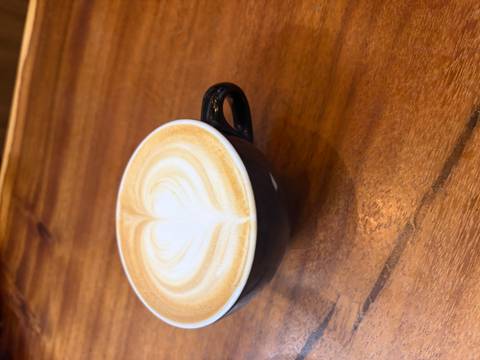 Cup of coffee with perfect heart latte art on polished wooden surface.