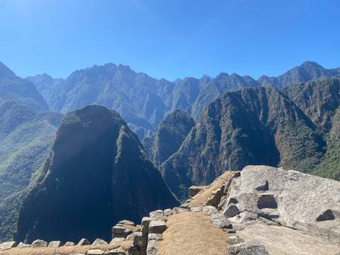 Panoramic Andes mountain spires surrounding Machu Picchu with bright blue sky.