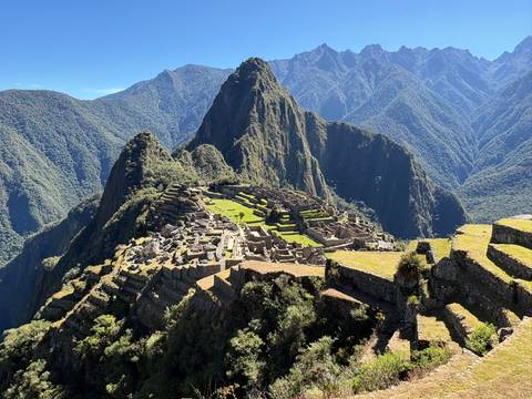 Iconic panoramic view of Machu Picchu’s stone terraces and Huayna Picchu peak surrounded by rugged Andes mountains.