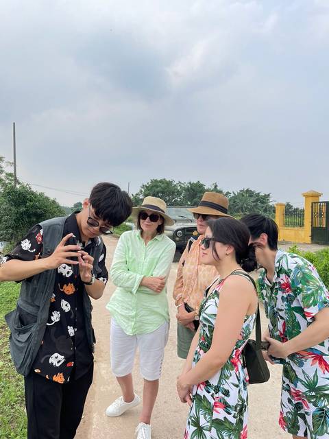 Guide showing a phone screen to small group of tourists on rural road with jeep behind