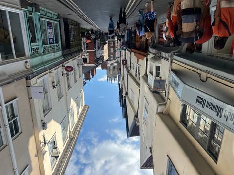 Narrow medieval street with shops leading to York Minster under a bright blue sky.