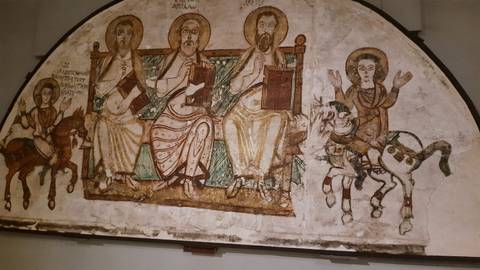 Ancient Christian wall painting showing saints and biblical figures in muted tones inside a museum.