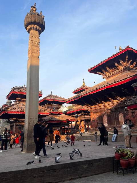 Historic pagoda-roofed temples with red canopies in Kathmandu Durbar Square illuminated by warm late-day light.