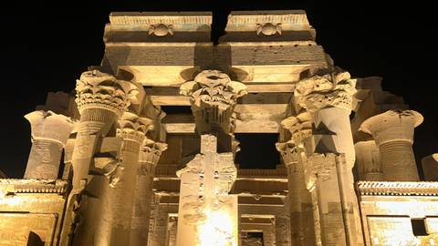 Night illumination of Kom Ombo Temple columns highlighting intricate carvings.