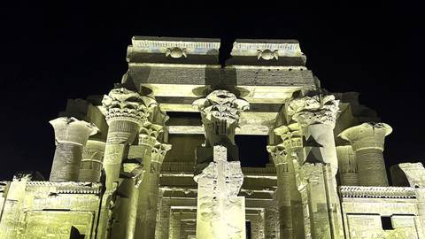 Nighttime lighting of Kom Ombo Temple columns casting dramatic shadows.