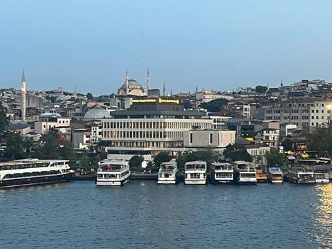 Evening waterfront view of Istanbul with ferries docked and illuminated mosques on the skyline.