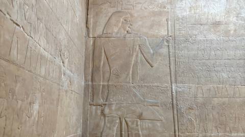 Interior stone wall relief depicting ancient Egyptian figure in profile within temple chamber.