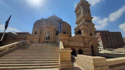 St George’s Greek Orthodox Church with wide stone staircase and bell tower under blue sky