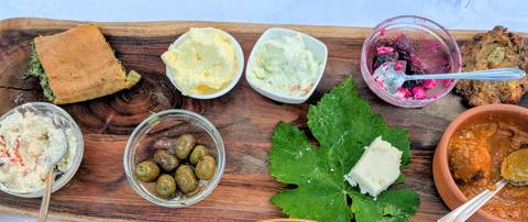 Rustic appetizer board with olives, cheeses, dips and bread on wooden platter