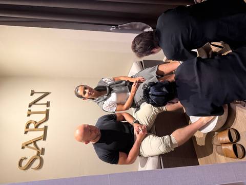 A couple receives a relaxing foot spa treatment from two attendants in a modern wellness center.