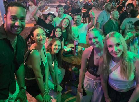 Night-time indoor party scene with friends smiling under colourful lighting in a bar