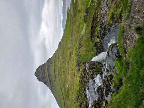 Iconic Kirkjufell mountain with cascading stream and small waterfall in foreground
